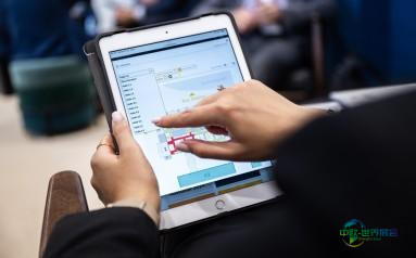 双手操作平板电脑,屏幕上显示着带有图表和彩色条带的软件界面