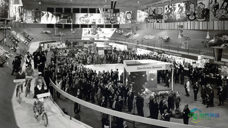 展厅内设置赛道的全景，观众站立在中央区域观看青年参赛者